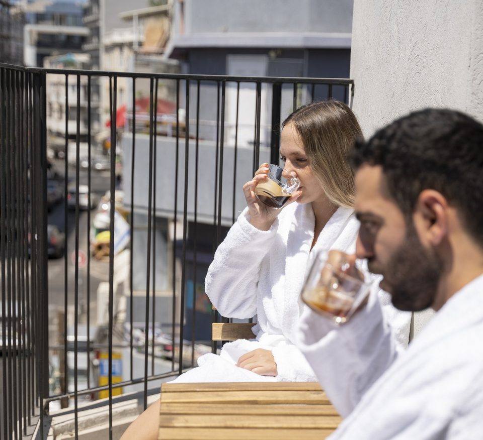 Des clients en peignoir boivent un café sur le balcon
