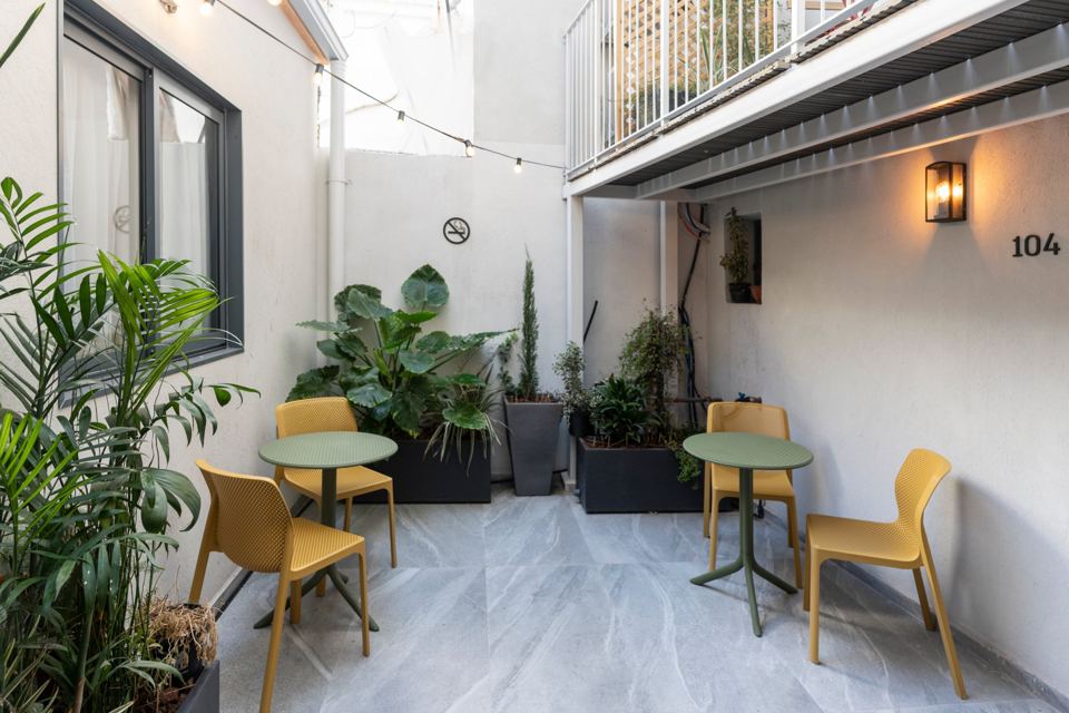 Cour jardin avec deux petites tables et des chaises jaunes