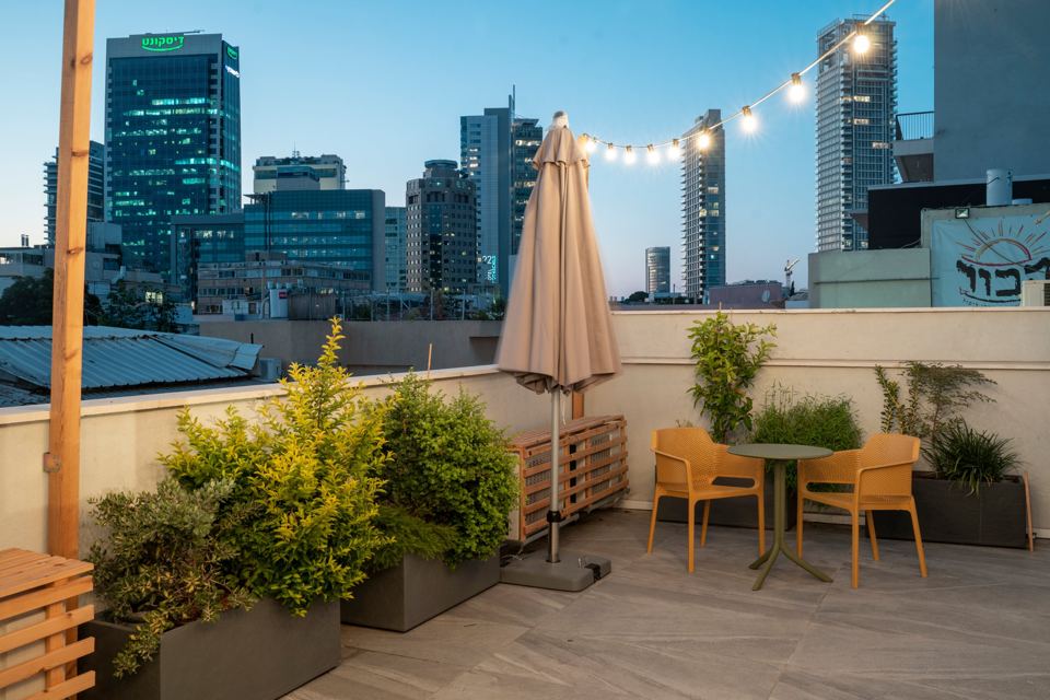 Toit de l'hôtel au crépuscule, guirlandes lumineuses et skyline de Tel Aviv